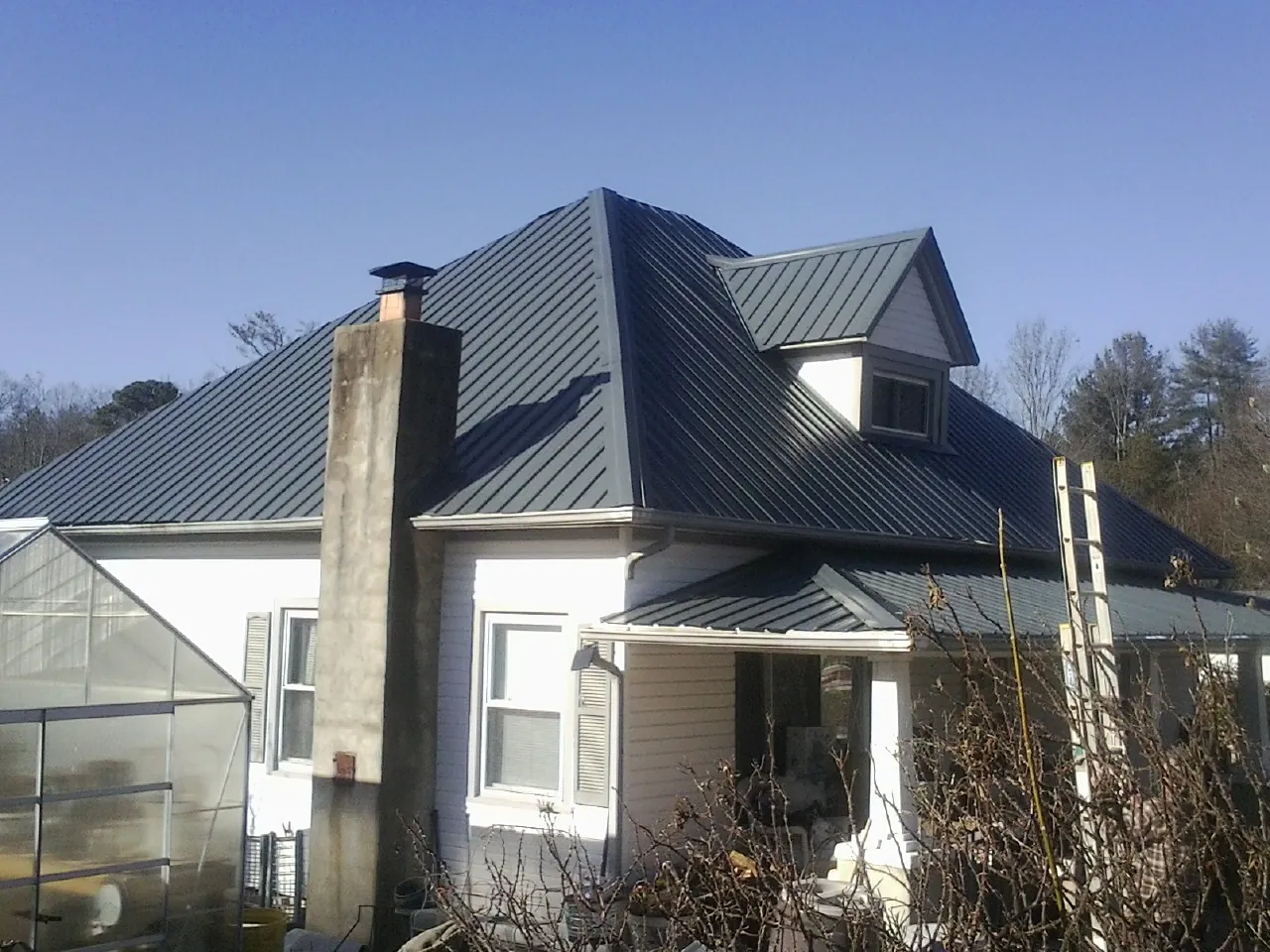 Dark blue standing seam metal roof on a white farmhouse with dormer — Slate & Tile Roof Repair by Roofing Brothers in Shelley