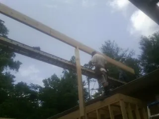 Carpenter setting a ridge beam over a new addition frame in Shelley