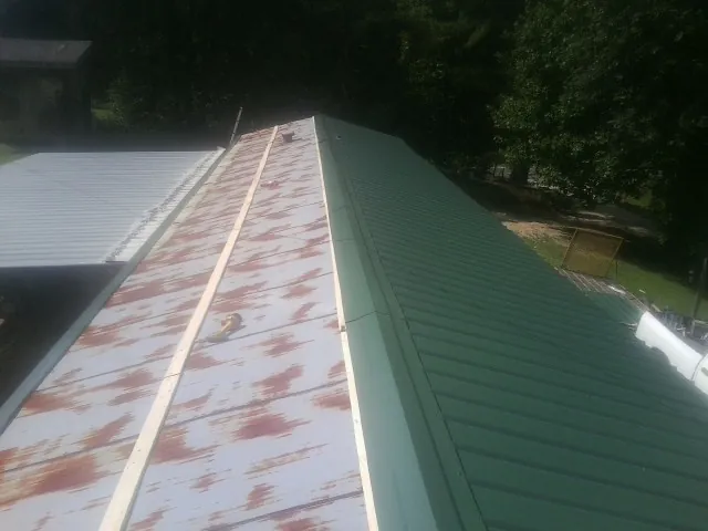 Old rusted panels beside newly installed green metal roofing — Wind Damage Roof Repair by Roofing Brothers in Shelley
