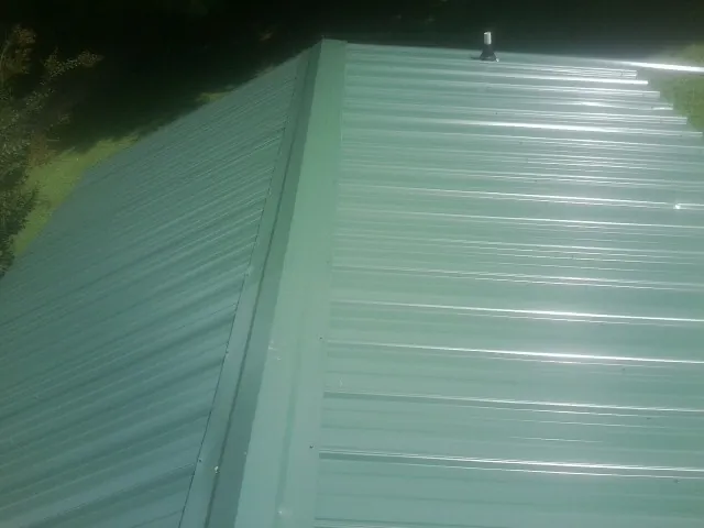 New green metal panels meeting at the ridge of a roof — Flat Roof Repair work by our crew in Shelley