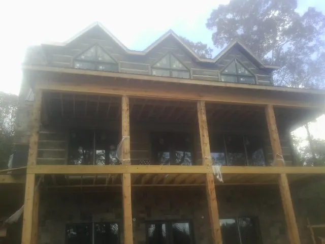 Dormers and porch framing on a large log home under construction — Roof Coating work by our crew in Shelley