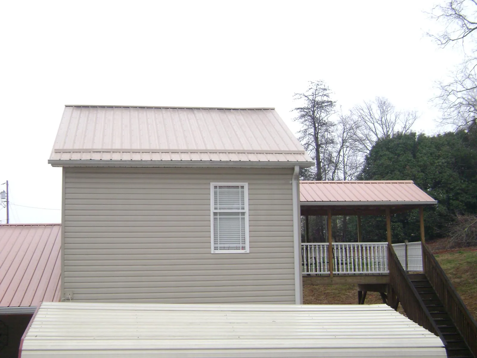 Tan metal roofs on a two story addition and attached porch, from a Roof Replacement job in Shelley